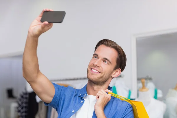 Egy mosolygó ember, a bevásárló szatyrok véve egy selfie — Stock Fotó