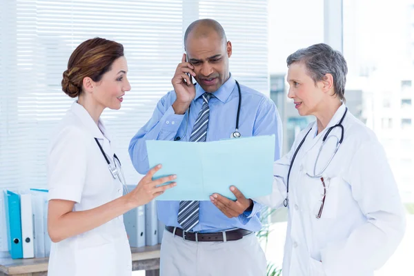 Doctor showing file to colleagues while calling — Stock Photo, Image