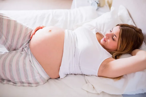 Lycklig gravid kvinna liggande på sängen — Stockfoto