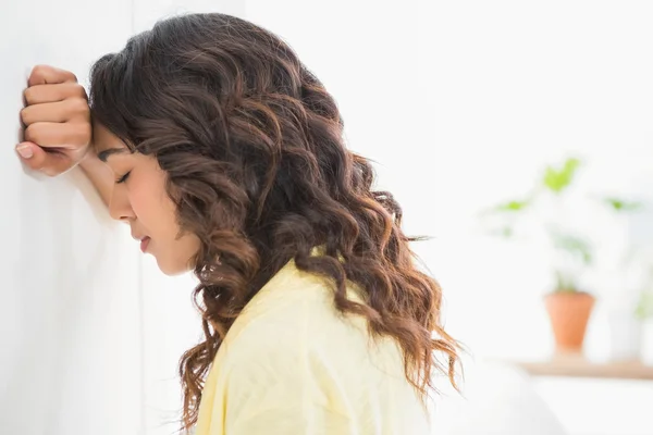 Thoughtful businesswoman facing and leaning against a wall — Stock Photo, Image