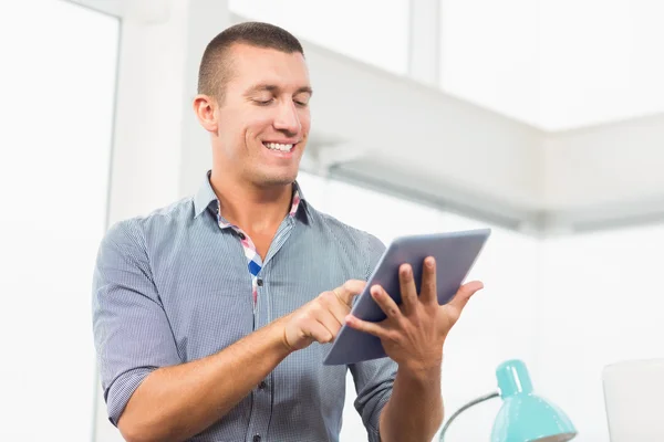 Empresário sorridente rolando em seu tablet — Fotografia de Stock