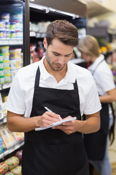 Mann schreibt im Supermarkt in Notizblock — Stockfoto