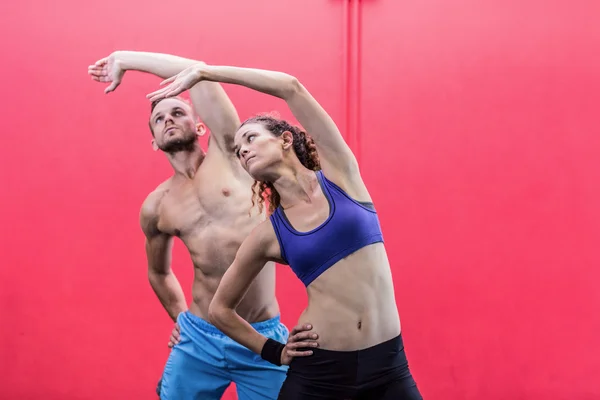 Muscular couple doing arms stretching — Stock Photo, Image