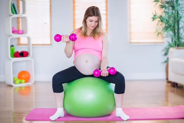 Беременная женщина поднимает гантели — стоковое фото