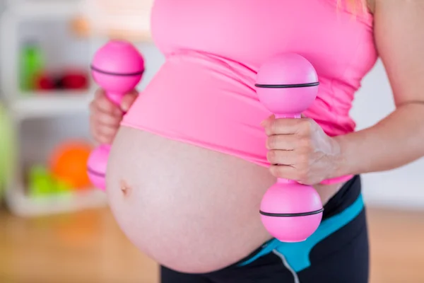 Una mujer embarazada sosteniendo pesas — Foto de Stock