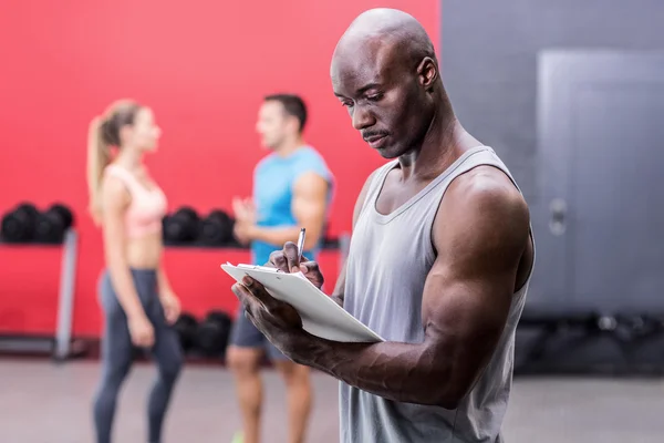 Allenatore muscolare attento che scrive sugli appunti — Foto Stock