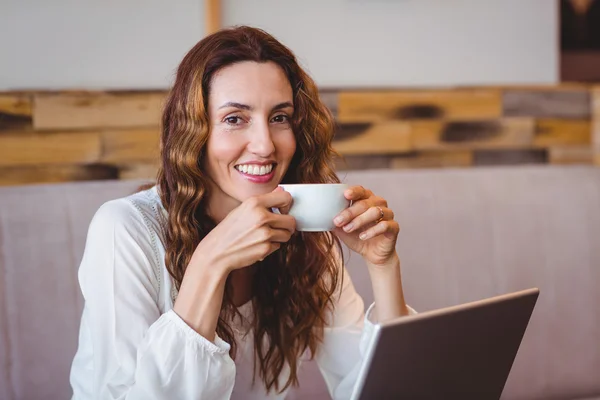 Morena tomando café usando laptop — Fotografia de Stock