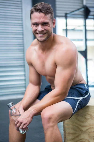 Retrato de homem muscular sorridente sentado e olhando para a câmera — Fotografia de Stock