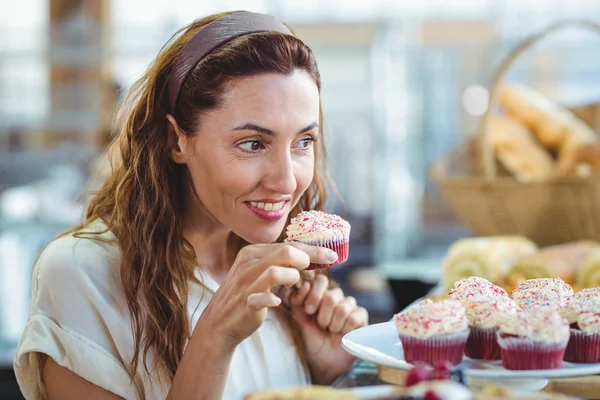 Pretty brunette holding and smelling cupcake — Stock Photo, Image
