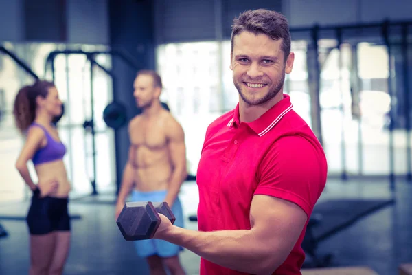 Muscular trainer lifting a dumbbell — Stock Photo, Image