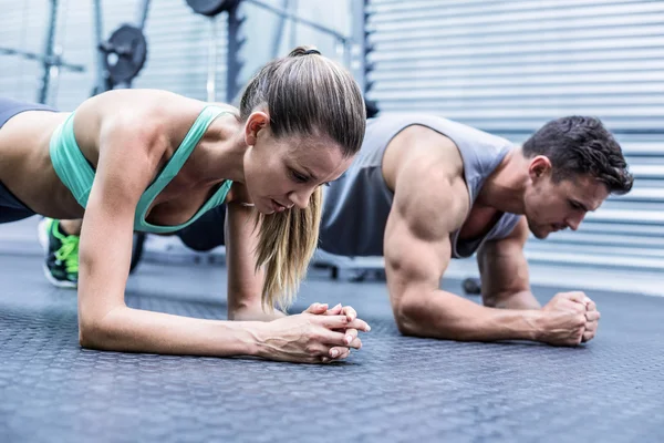 Casal muscular fazendo exercícios de prancha — Fotografia de Stock