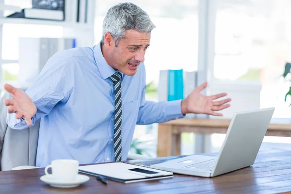 Förvirrad affärsman tittar på bärbar dator — Stockfoto