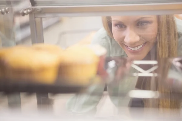 Portrait d'une femme regardant de nouvelles assiettes avec des pâtisseries — Photo