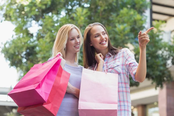 Kvinnor med shopping väskor och pekar bort — Stockfoto