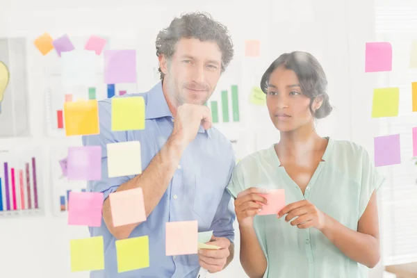 Puzzled business team looking post its on the wall — Stock Photo, Image