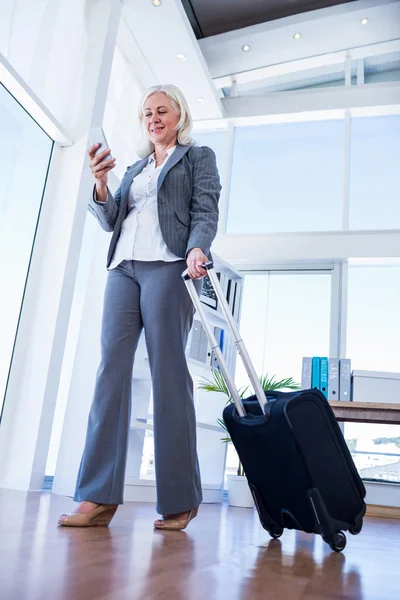 Деловая женщина с помощью смартфона и с чемоданом — стоковое фото
