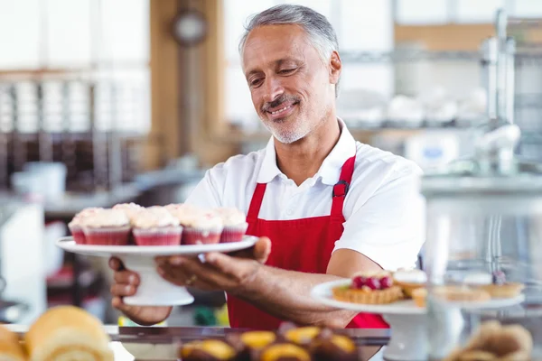 Barista holding plate of cupcakes — Stock Photo, Image