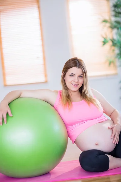 Беременная женщина рядом с мячом для упражнений — стоковое фото