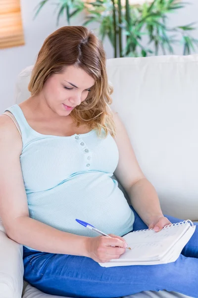 Mujer embarazada escribiendo algunas notas — Foto de Stock