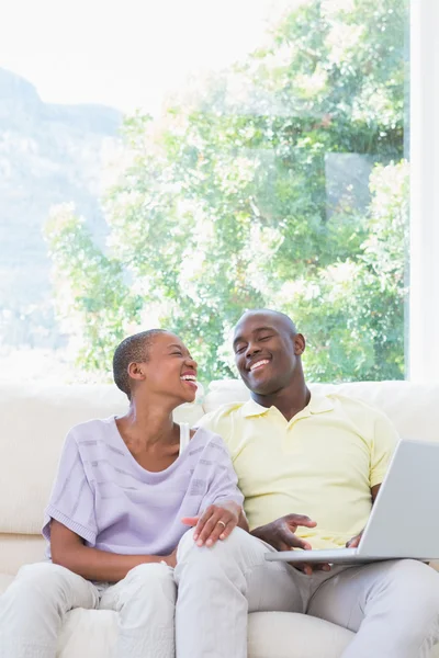 Feliz casal sorrindo usando laptop no sofá — Fotografia de Stock