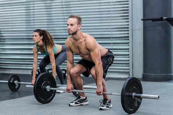 Muscular couple lifting weight together — Stock Photo, Image
