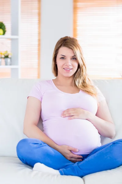 怀孕的女人看着相机用手在肚子上 — 图库照片