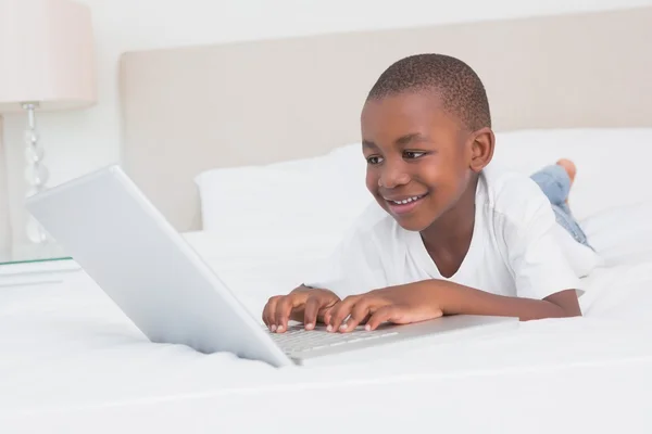 Niño bonito usando el portátil en la cama —  Fotos de Stock