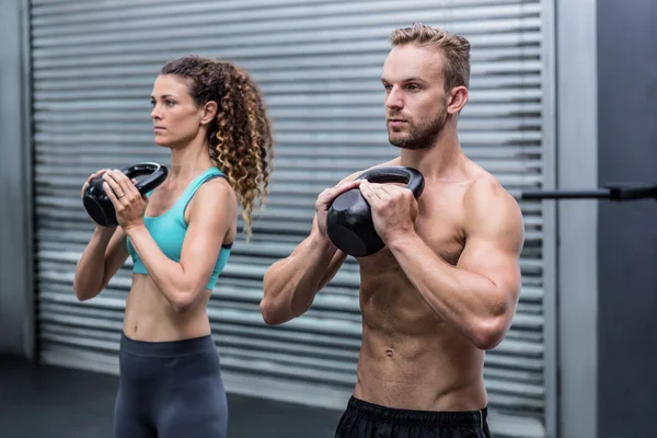 Casal muscular exercitando com kettlebells — Fotografia de Stock