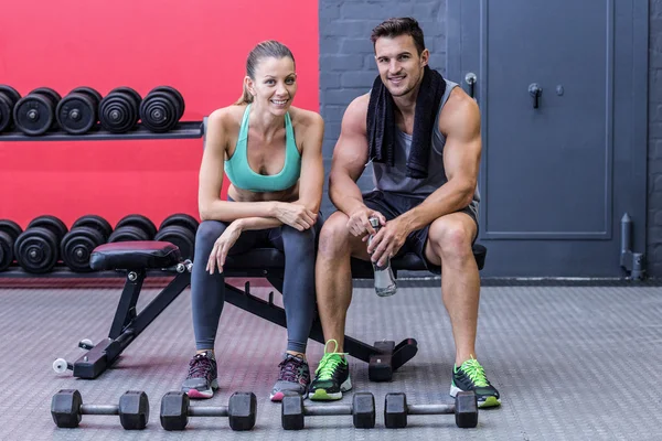 Muscular couple sitting on a bench — Stock Photo, Image