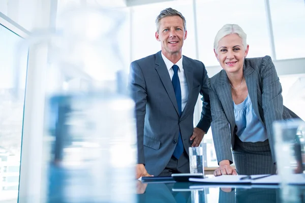 Geschäftsleute blicken hinter Schreibtisch auf Kamera — Stockfoto