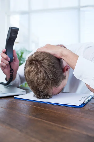 Irritated businessman holding a land line phone — Stock Photo, Image