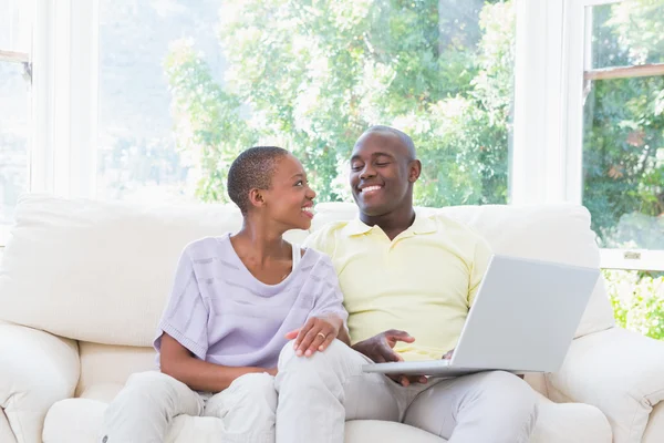 Feliz casal sorrindo usando laptop no sofá — Fotografia de Stock