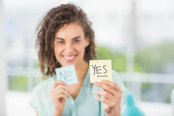 Smiling businesswoman holding yes and no sticks — Stock Photo, Image