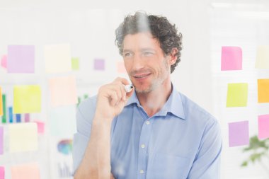 Puzzled businessman looking post its on the wall clipart