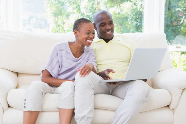 Feliz casal sorrindo usando laptop no sofá — Fotografia de Stock