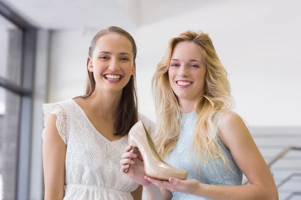 Gelukkig vrouwen glimlachen op camera en tonen een hak schoen — Stockfoto