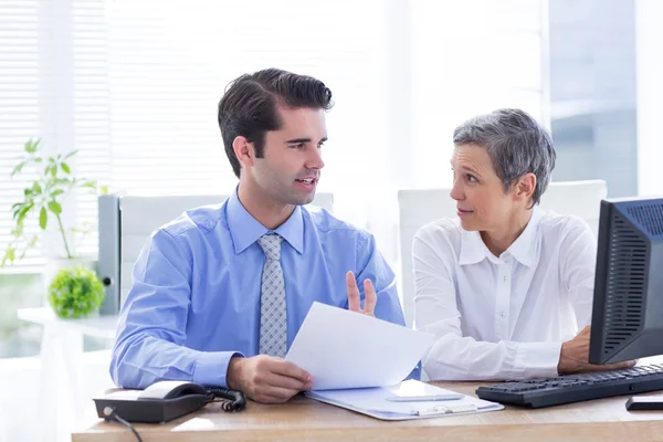 Zwei Geschäftsleute betrachten ein Papier, während sie an einem Ordner arbeiten — Stockfoto