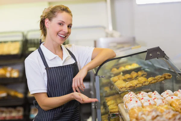 Retrato de una pastelera rubia sonriente mostrando una pastelería — Foto de Stock