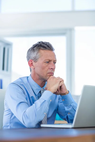 Homem de negócios concentrado olhando para o computador portátil — Fotografia de Stock