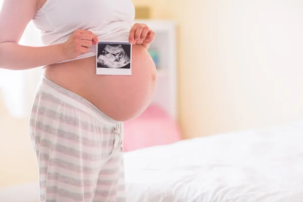 Mujer embarazada mostrando ecografías —  Fotos de Stock