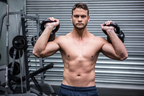 Ritratto di uomo muscoloso che solleva due kettlebell — Foto Stock