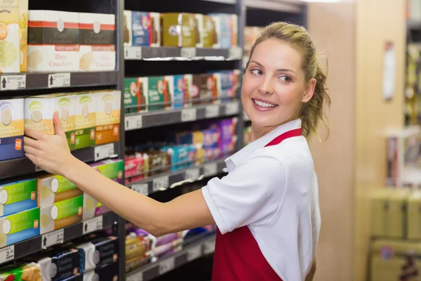Travailleur blonde souriante prenant un produit dans une étagère — Photo