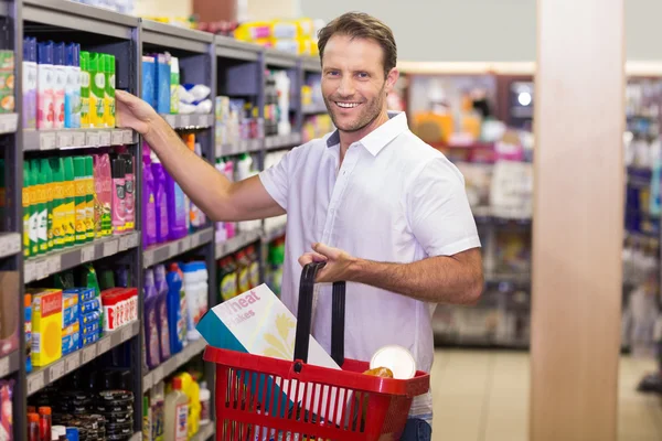 Retrato de un guapo sonriente tomando un producto en un estante —  Fotos de Stock