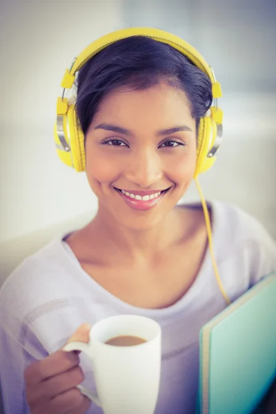 Casual businesswoman is drinking coffee while listening to music — Zdjęcie stockowe
