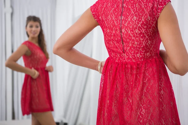 Smiling woman trying on a red dress — Stock Photo, Image