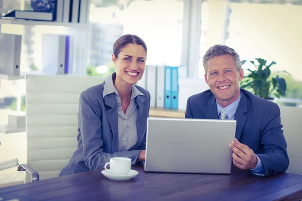 Business people looking at camera and using laptop — Stock Photo, Image