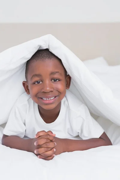 Hübsch lächelnder kleiner Junge im Bett — Stockfoto