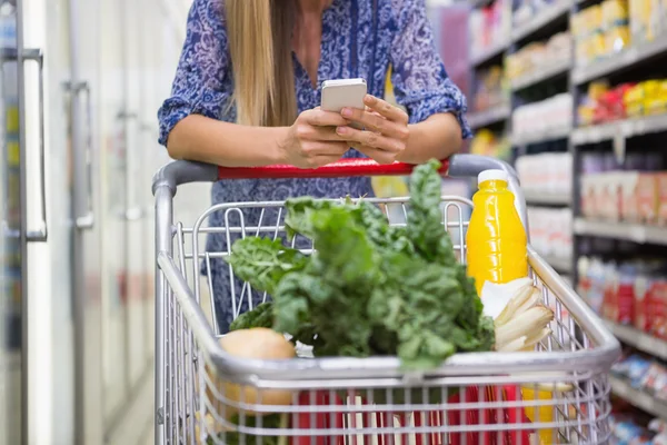 Kvinna köpa produkter och använda sin smartphone — Stockfoto