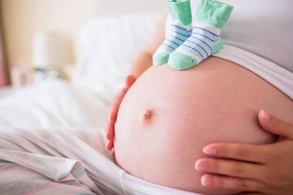 Zwangere vrouw met baby schoenen over hobbel — Stockfoto