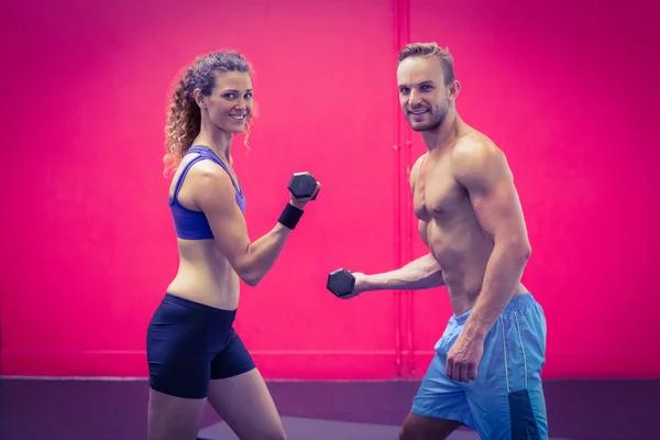 Muscular couple lifting dumbbells — Stock Photo, Image
